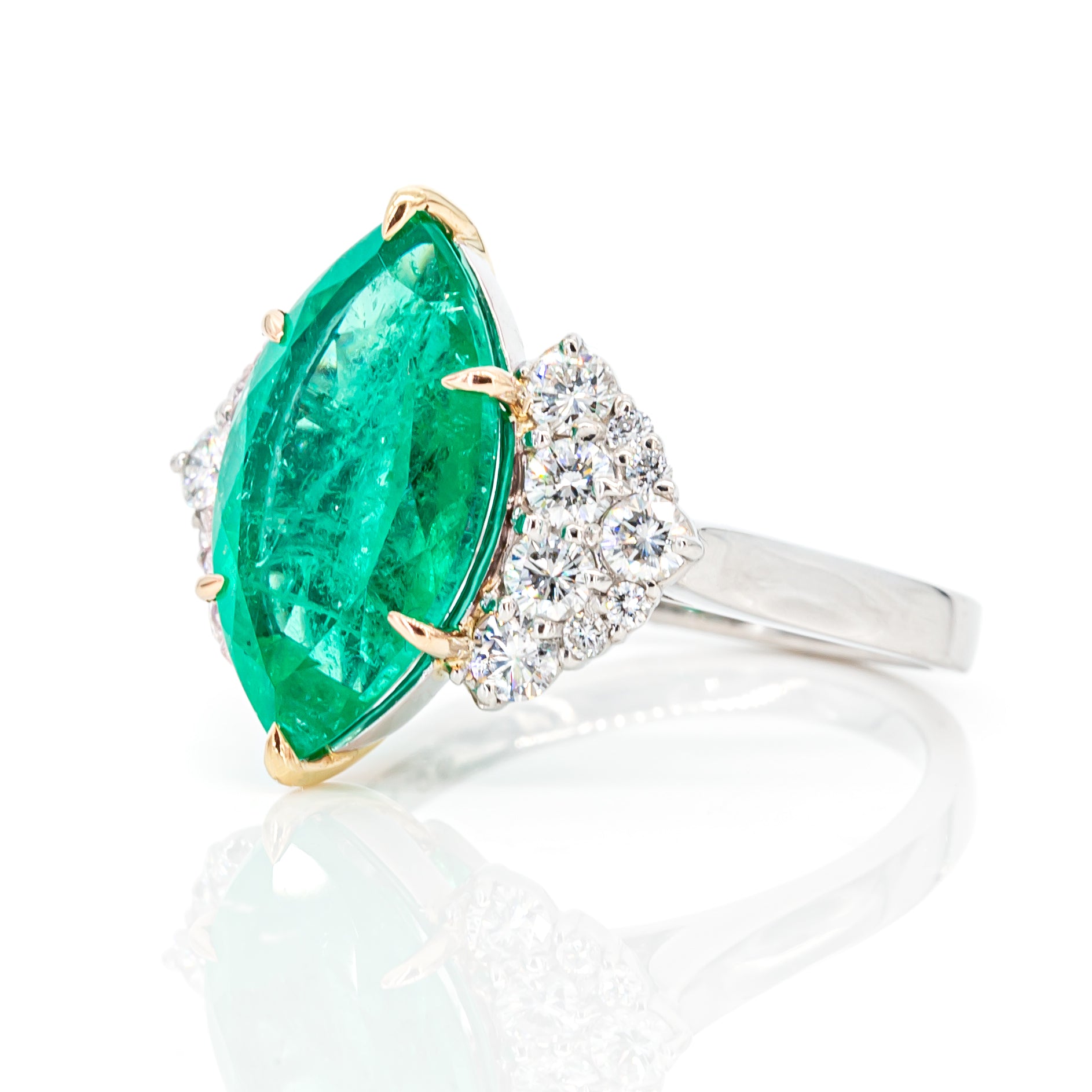 Angled perspective of Colombian emerald and diamond ring in PT900 platinum and 18K yellow gold
